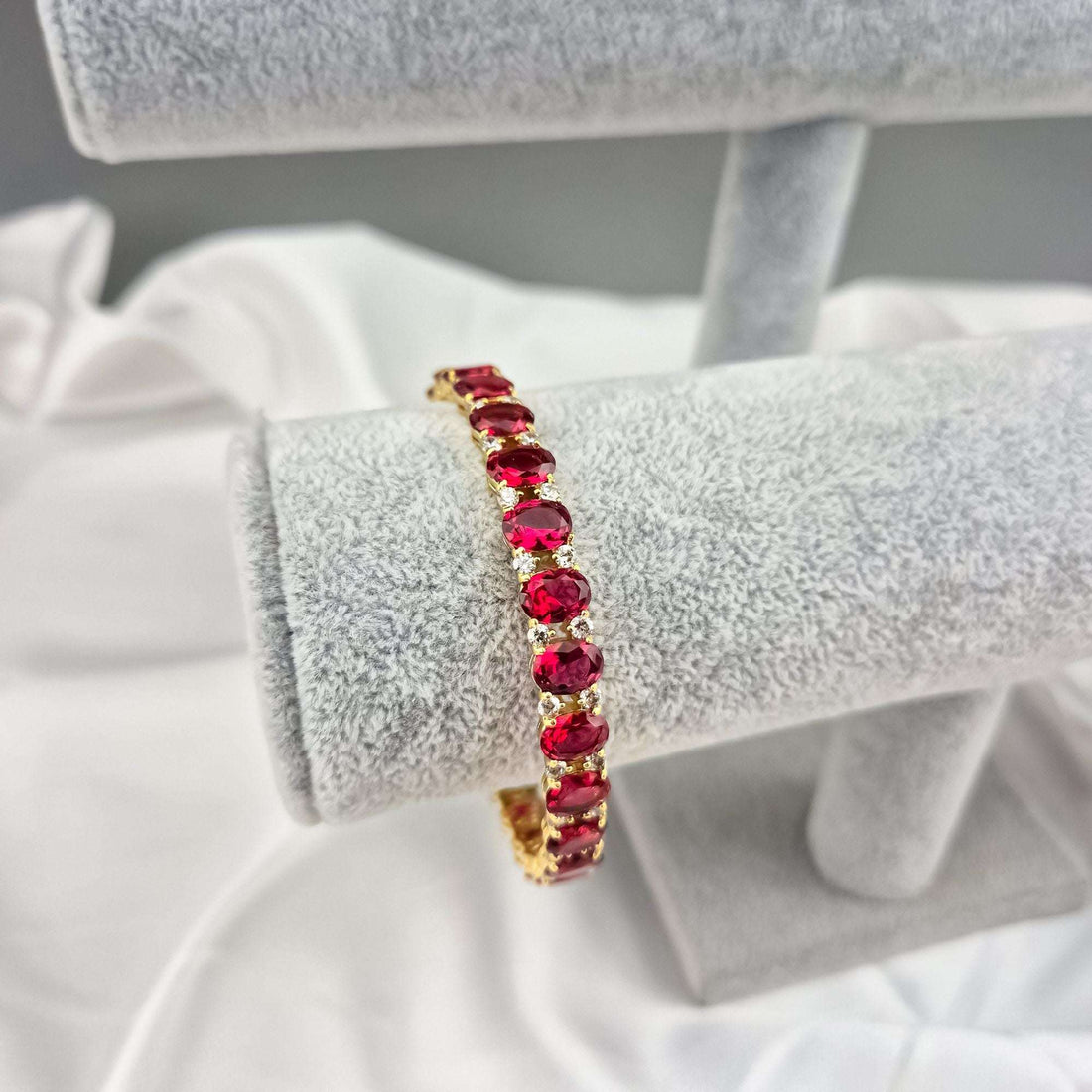 Gold-plated red crystal bracelet on a jewellery stand, close-up side view