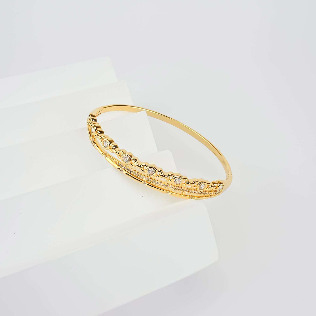 Multi-row gold-plated bracelet with sparkling cubic zirconia on a white stand