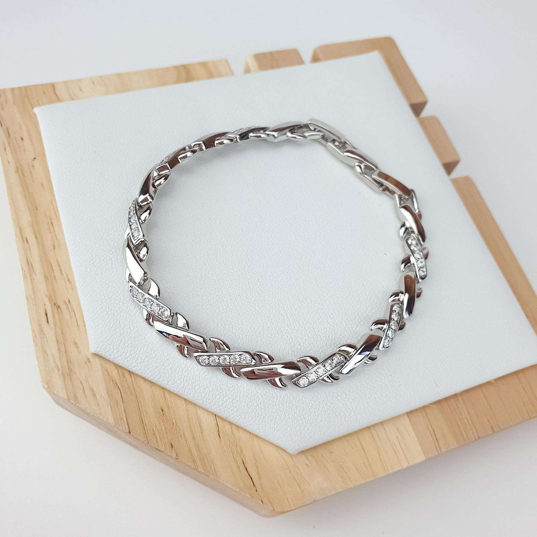 Platinum-plated bracelet on a wooden stand, close-up of shiny links and stones