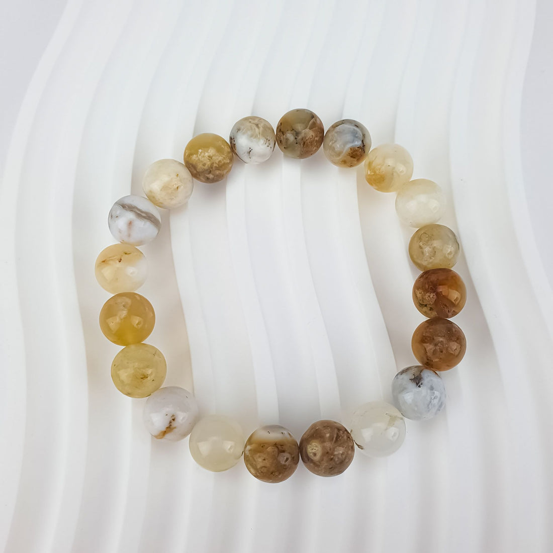 Opal bead bracelet close-up on a ribbed white surface, each bead a different shade