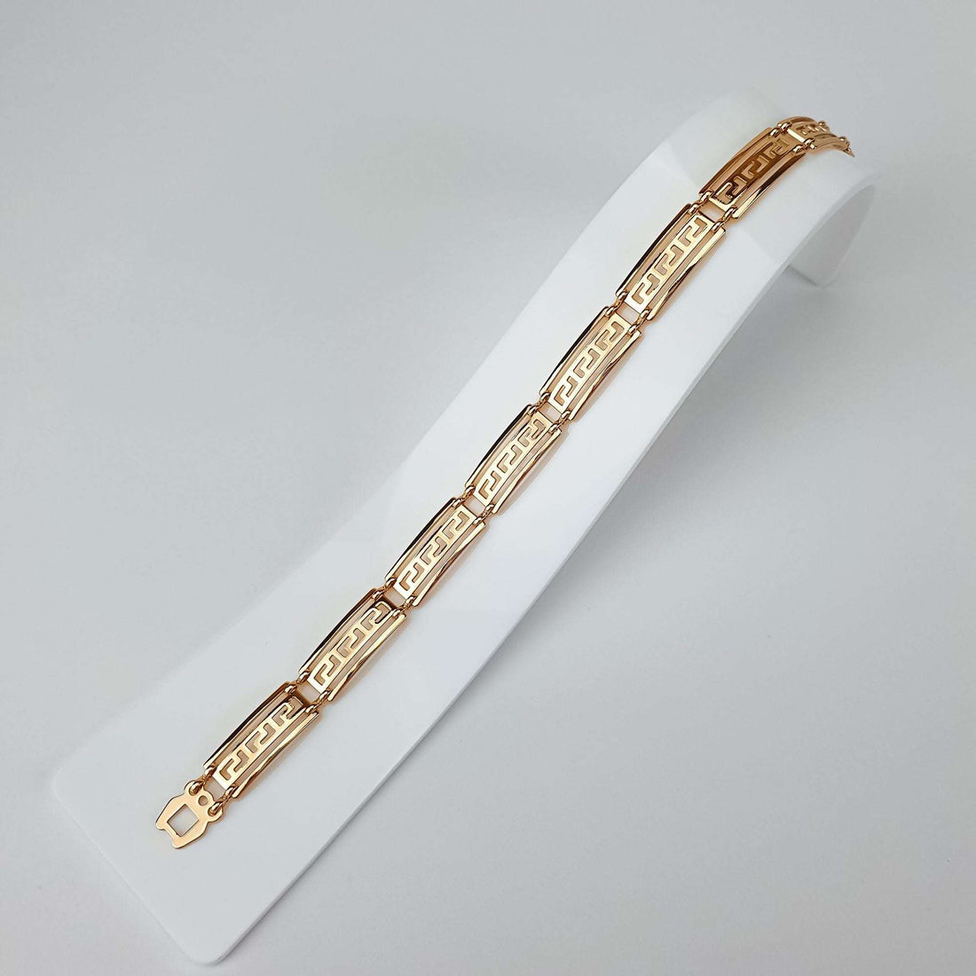 Gold-plated Greek meander bracelet laid out in full length on a white stand