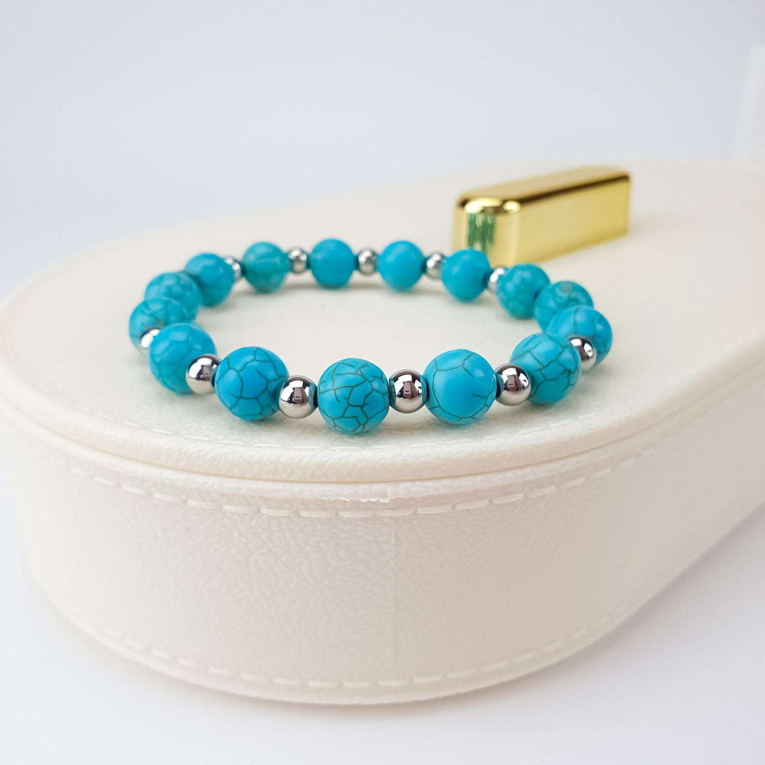 Stretch turquoise howlite bracelet with silver-tone spacers on a white box