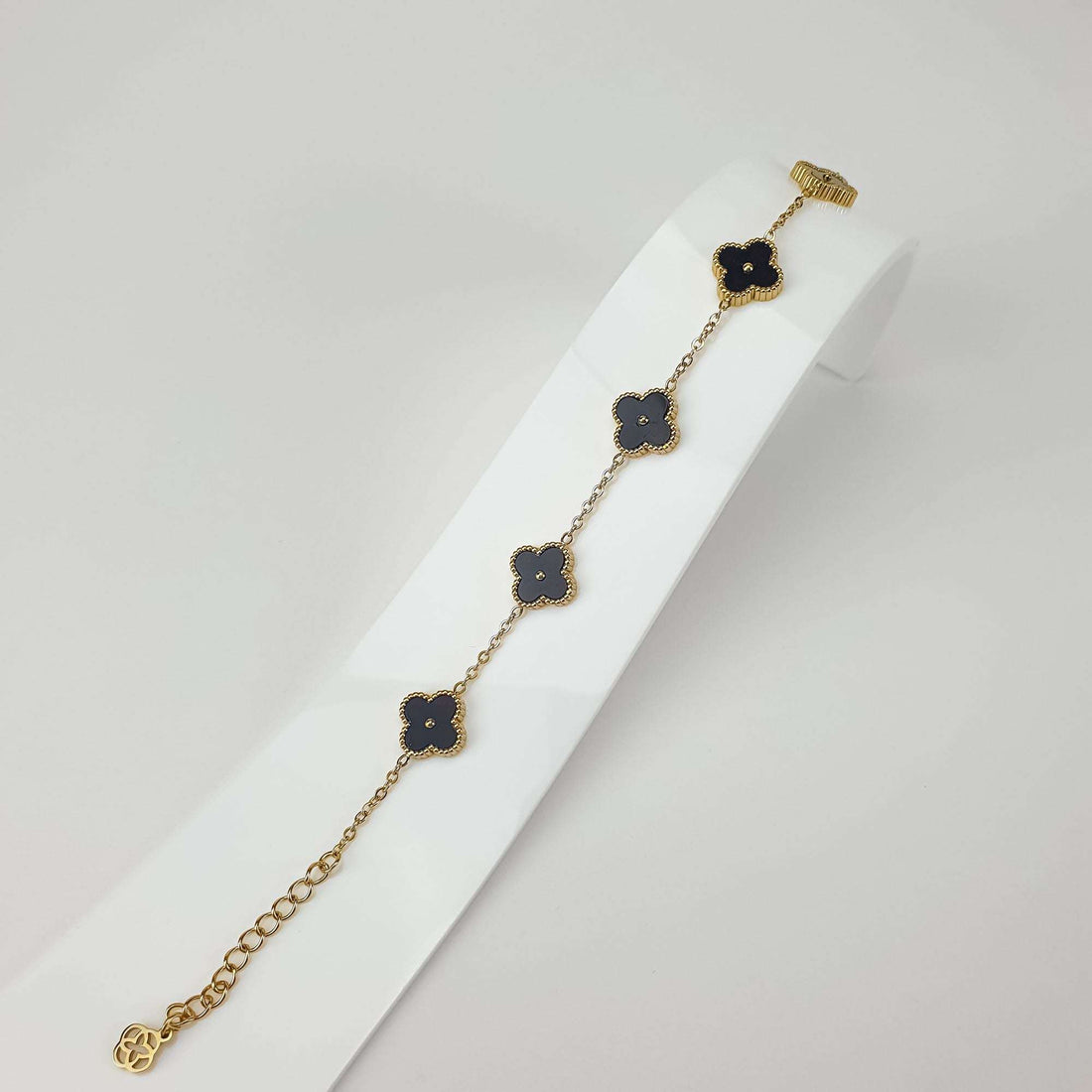 Bracelet with five black clover charms and adjustable chain on a white stand