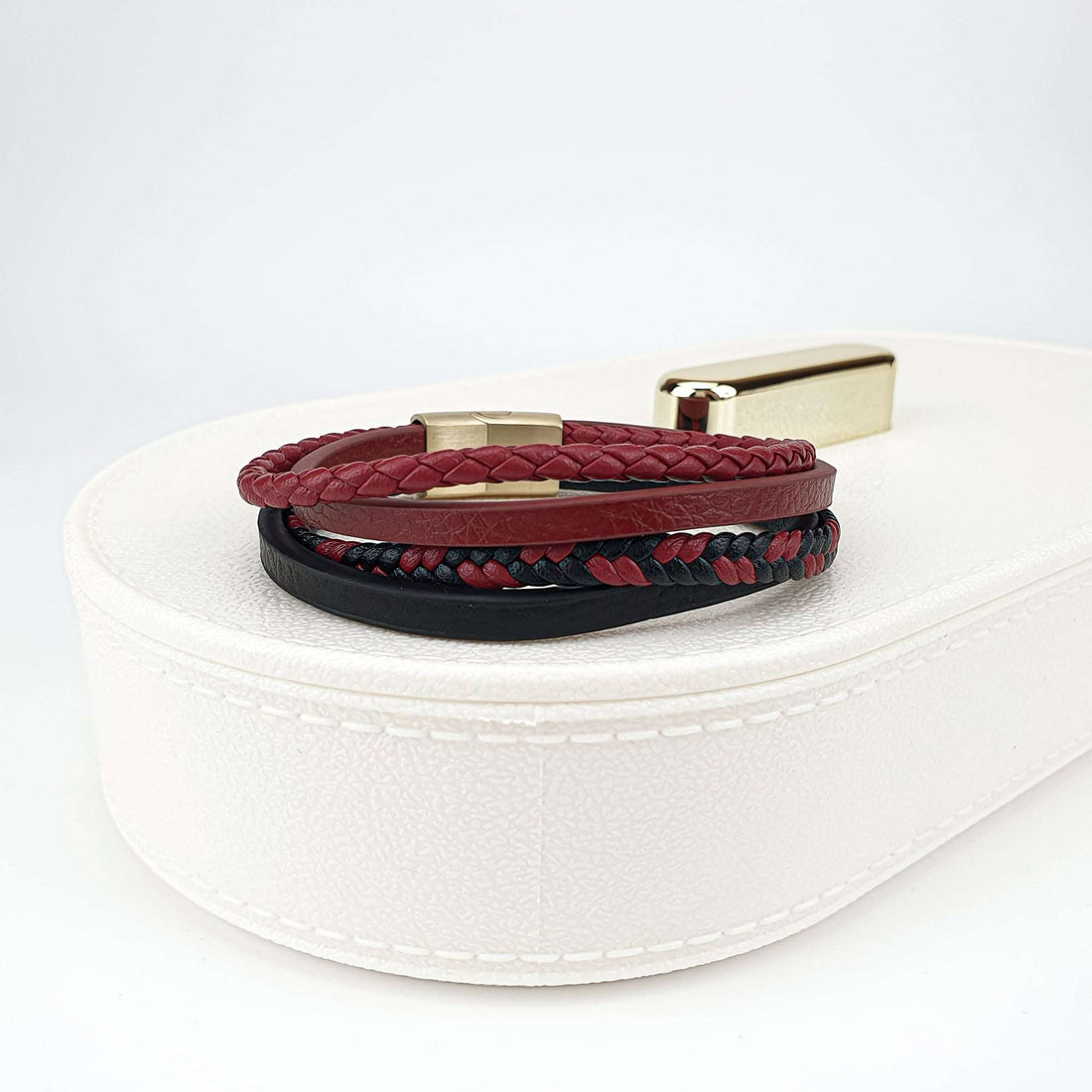 Red and black braided and smooth leather straps on a white jewellery box