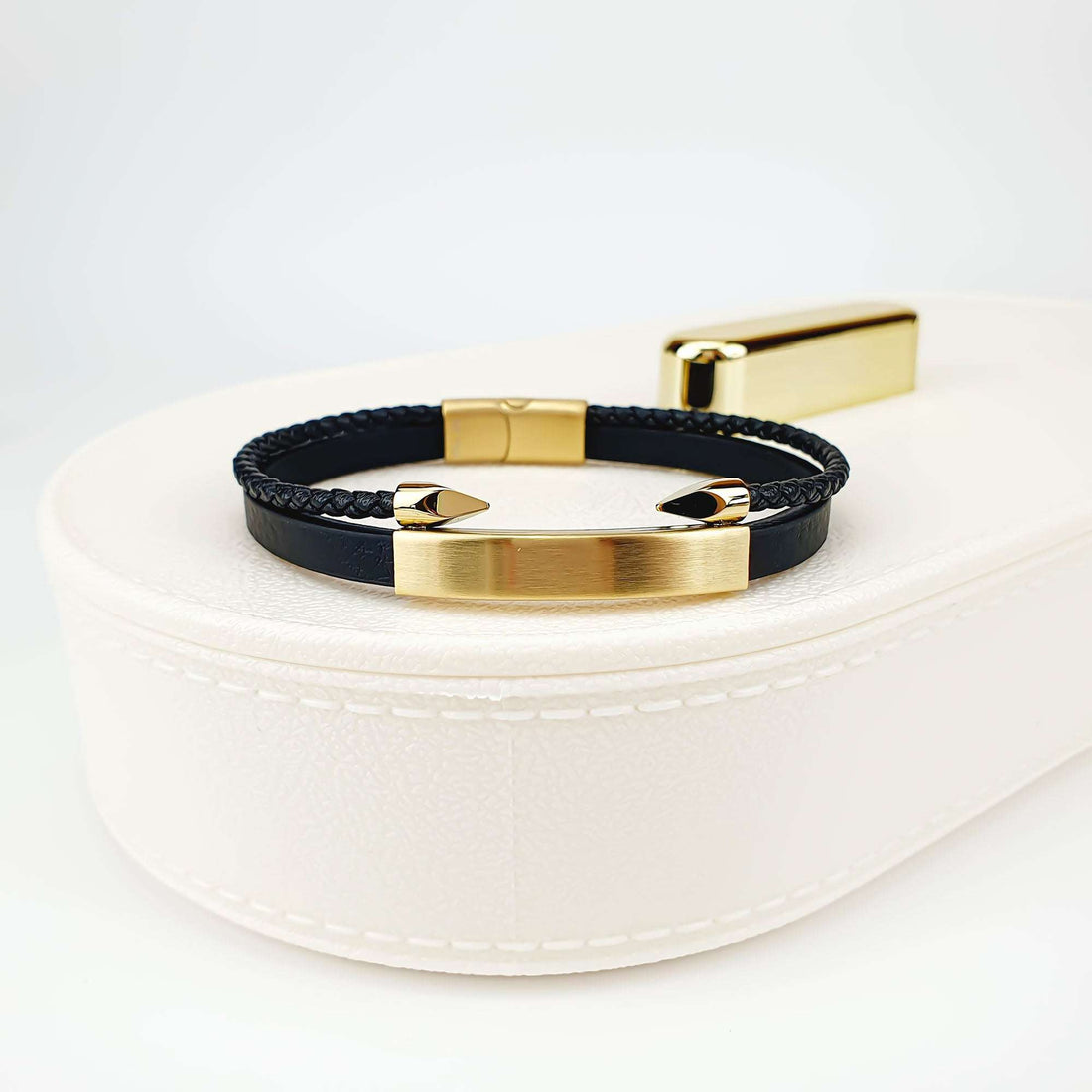 Braided and smooth leather bracelet with a gold-plated bar on a white jewellery box