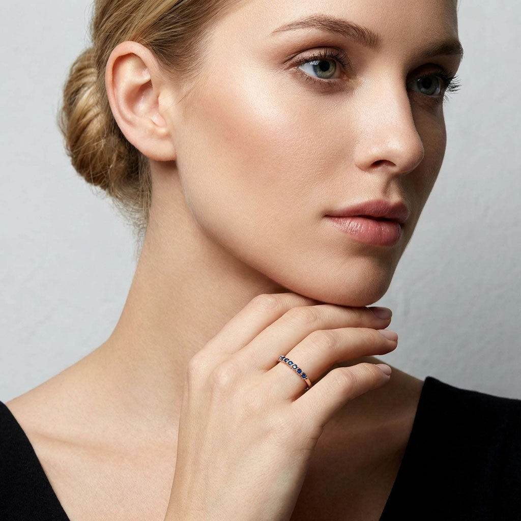 Blue crystal ring in rose gold tone on a model's hand near her face