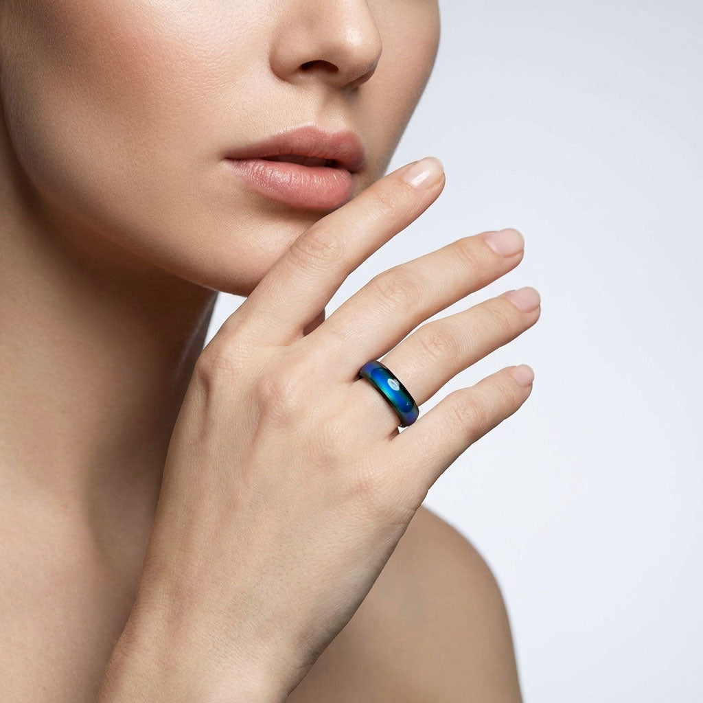 Black-rimmed mood ring on a model's finger showing a blue green shift