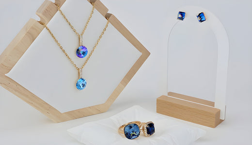 Gold-plated jewellery set with blue crystal pendants, earrings and rings on wooden stands