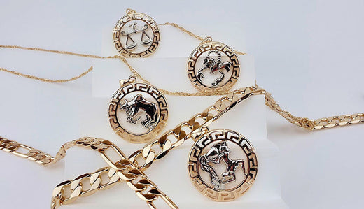 Gold-plated zodiac medallions on fine chains and chunky bracelets on white stands
