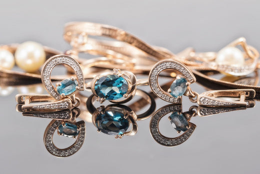 Gold-plated earrings and a ring with bluish stones and cubic zirconia on a mirror