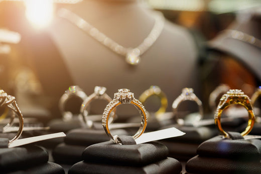 Sparkling rings on dark stands and a necklace in a warmly lit display case