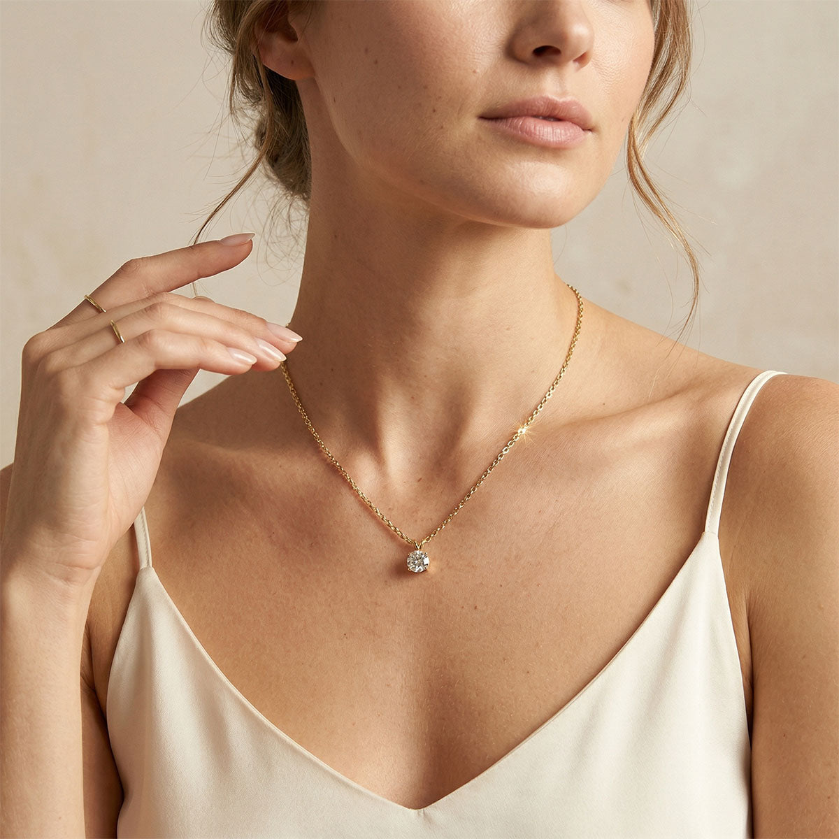 Fine gold-plated chain with a sparkling stone pendant on a woman in pale silk