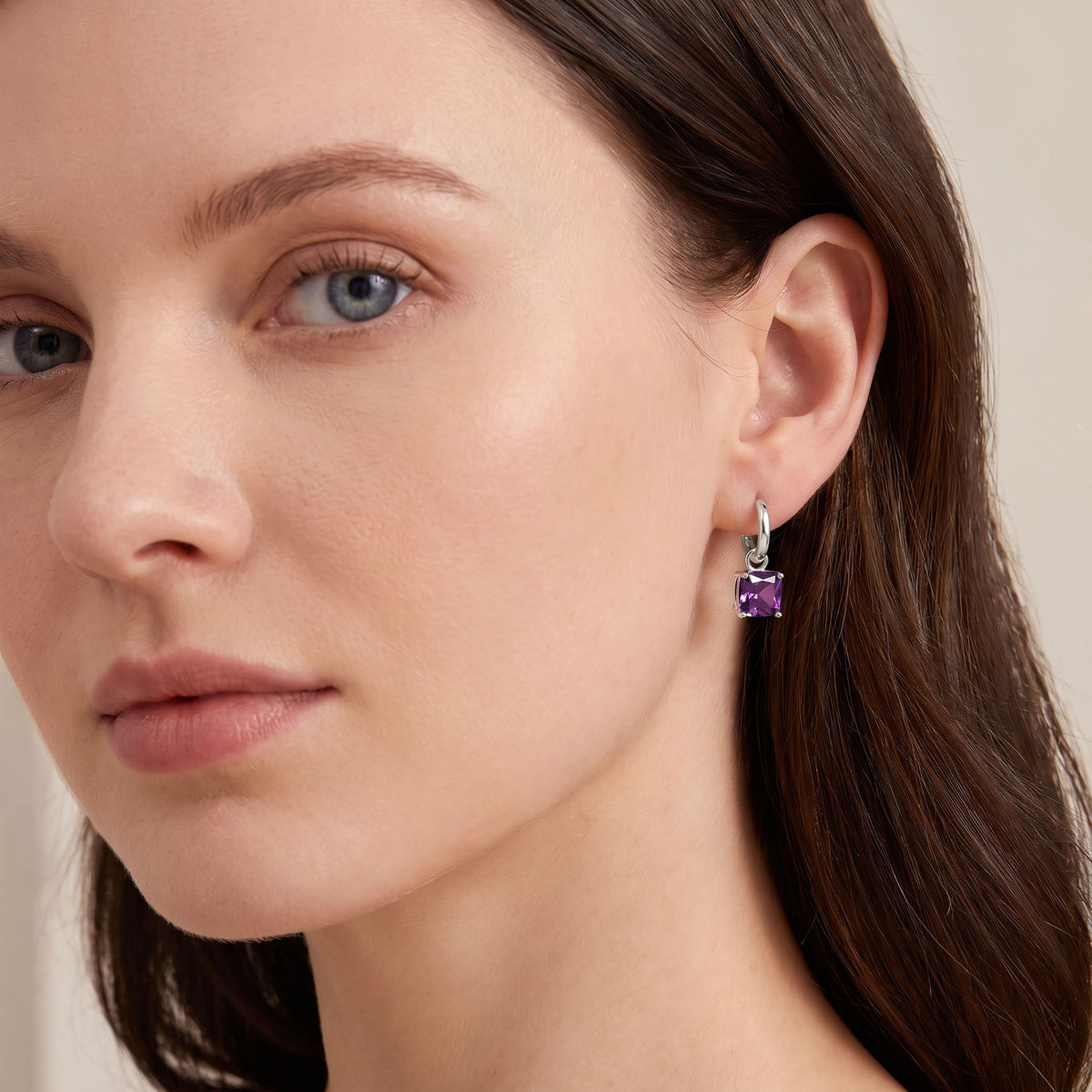 Silver | Model wearing a silver-tone hoop earring with a violet crystal drop