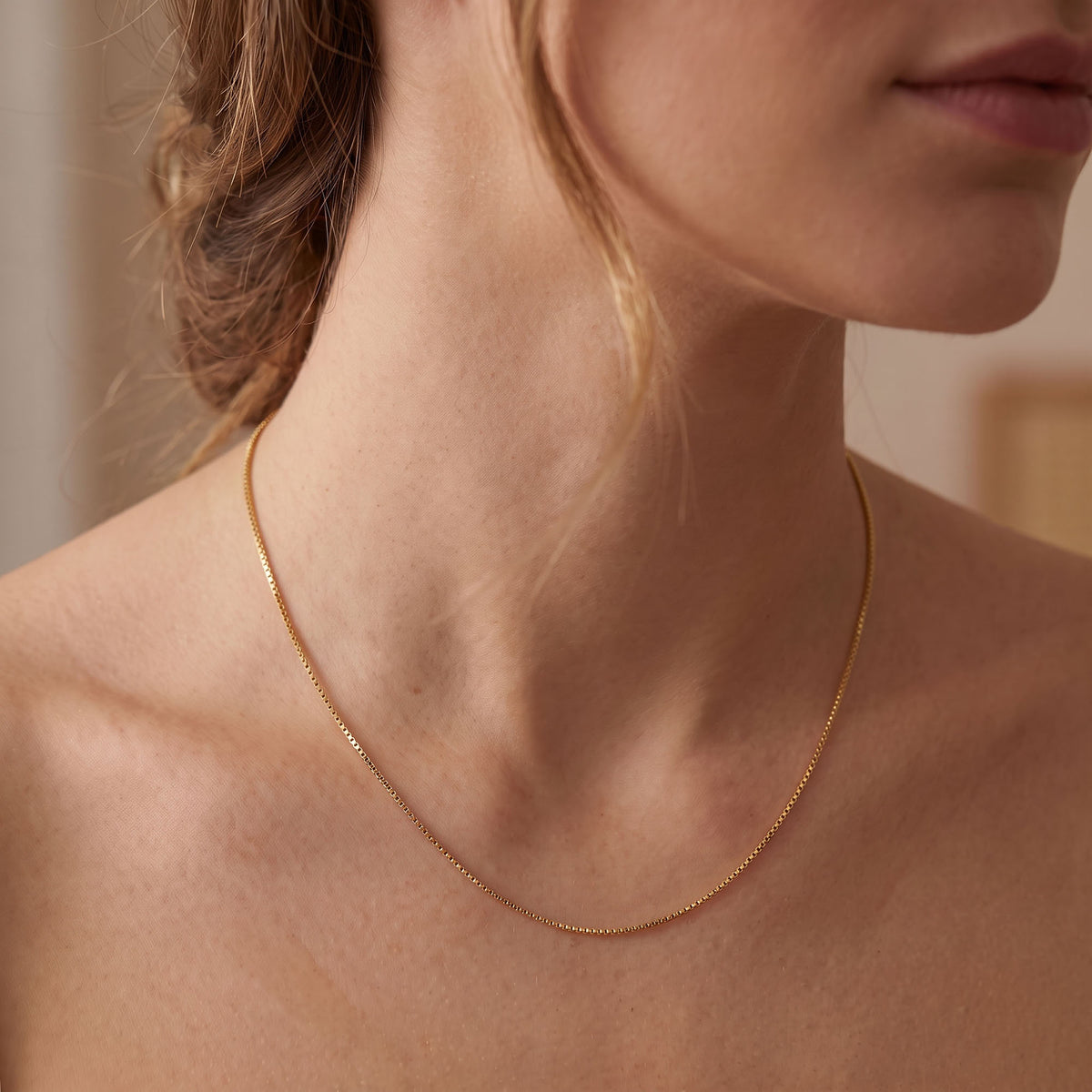 Woman wearing a thin gold-tone Venetian chain on the collarbones