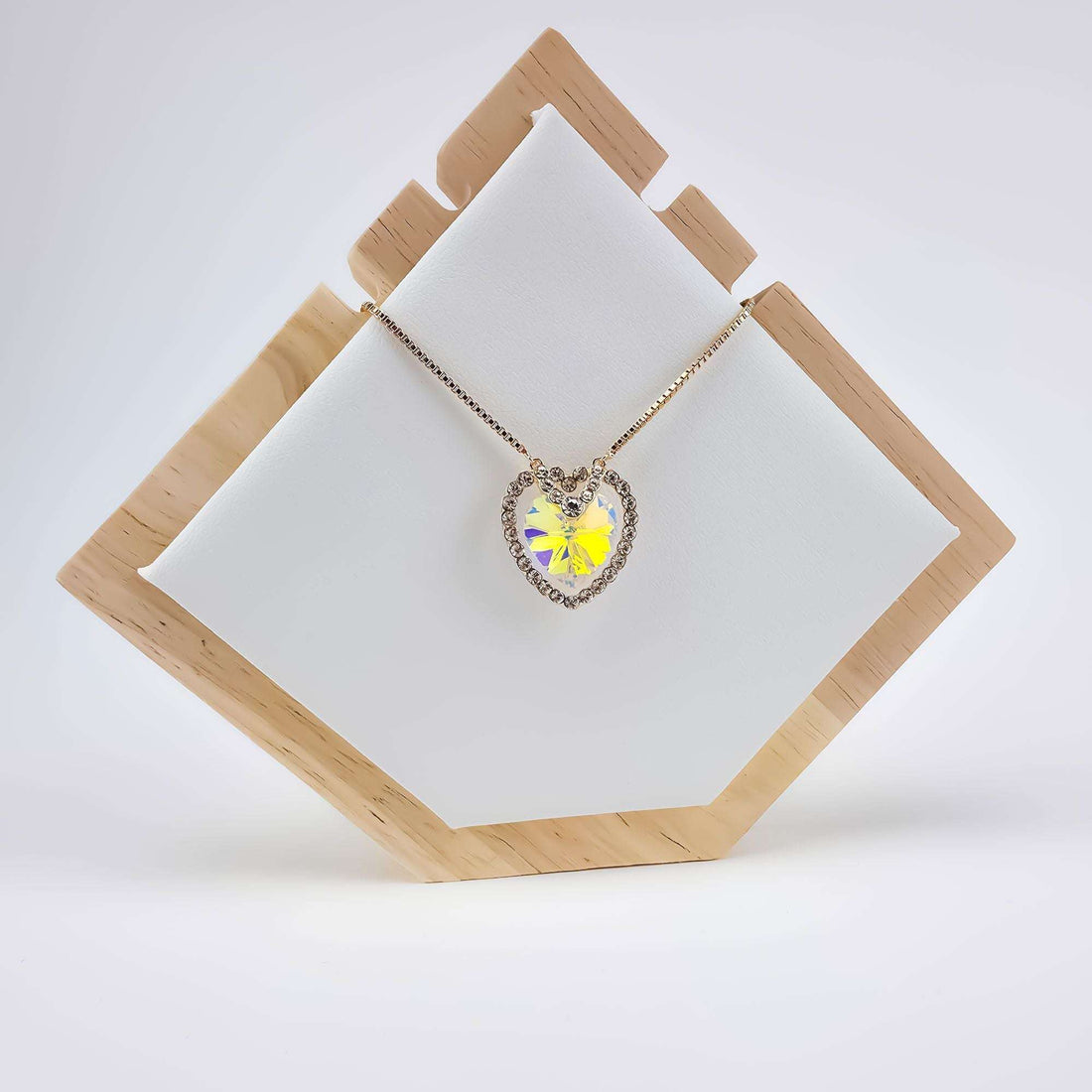 Heart pendant necklace on a wooden stand, crystal shimmering in rainbow colours