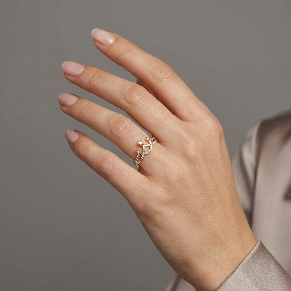 Gold-plated crown ring with white stones on a model's finger, grey background
