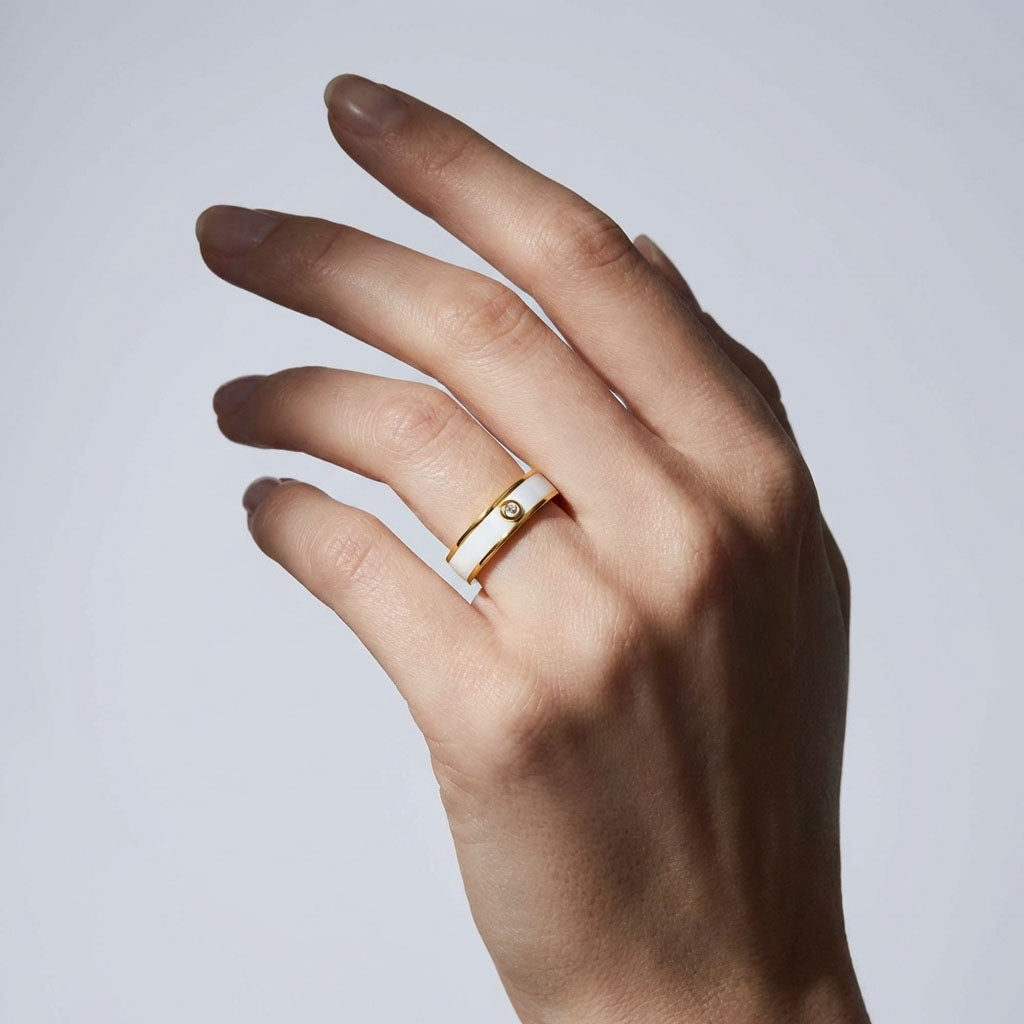 Gold-plated ceramic ring worn on a woman's ring finger, light background