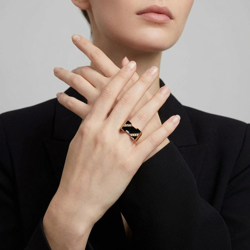 Model in a black jacket showing a chunky gold-plated black enamel ring
