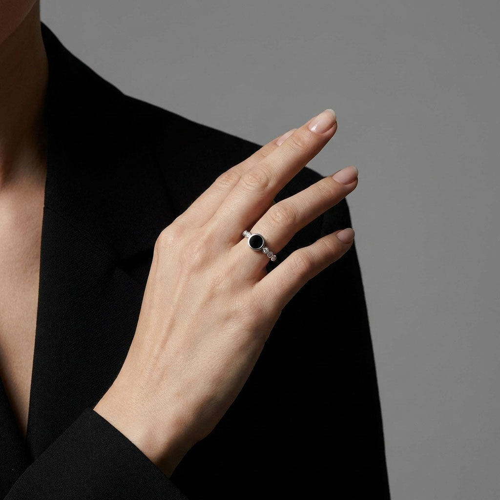 Woman's hand wearing the black disc ring on the shoulder of a dark jacket