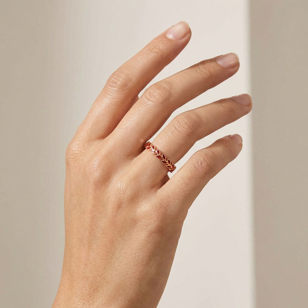 Model wearing the red enamel leaf ring on her ring finger, neutral background
