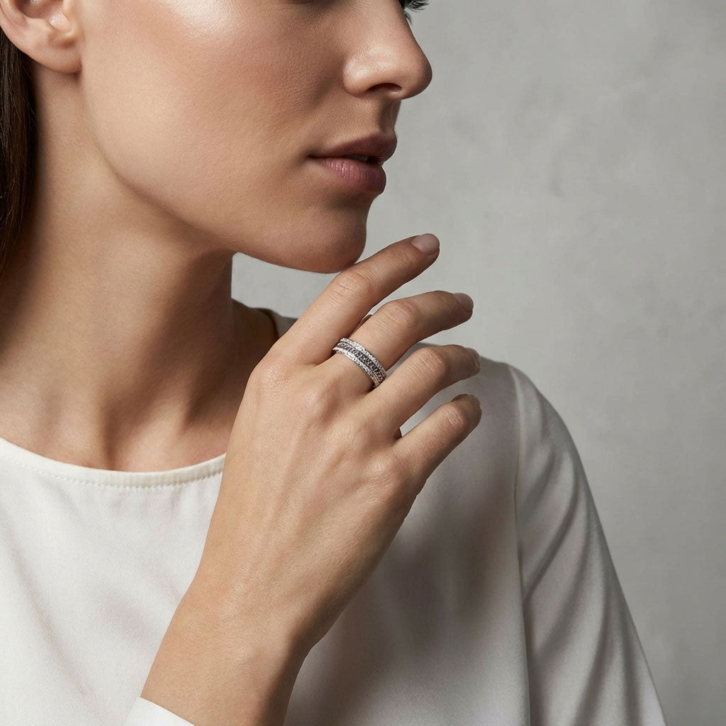 Model wearing a platinum-tone chain ring on her finger by a light wall
