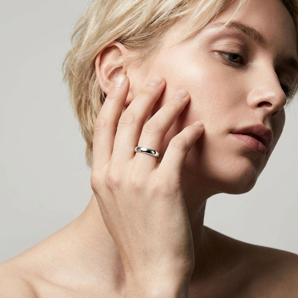 Woman with a smooth silver-tone wedding ring, hand resting on her cheek