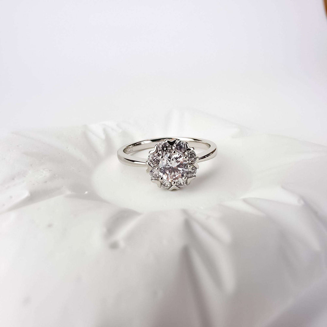 Platinum-plated ring with a cubic zirconia flower rosette on a white cushion