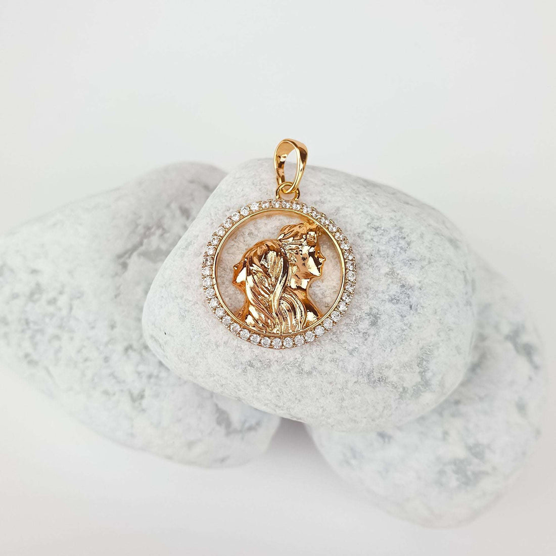 Couple silhouette pendant at an angle on pale pebbles, sparkling cubic zirconia border