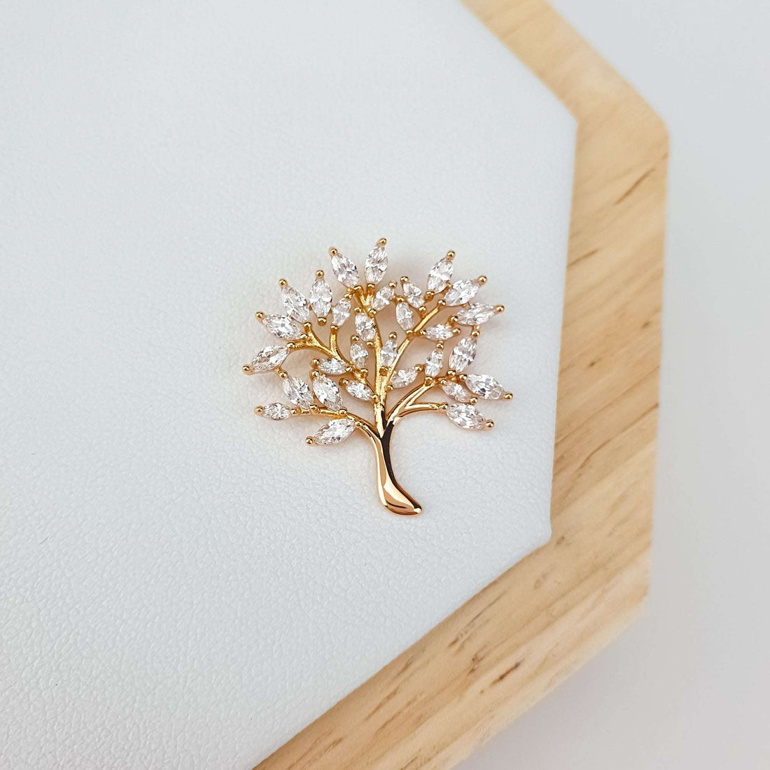Gold-tone tree of life pendant on light leather, close-up of sparkling leaves