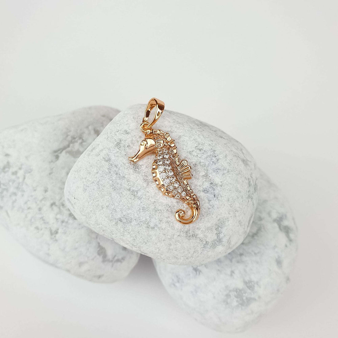 Gold-tone seahorse pendant with sparkling cubic zirconia on light river stones