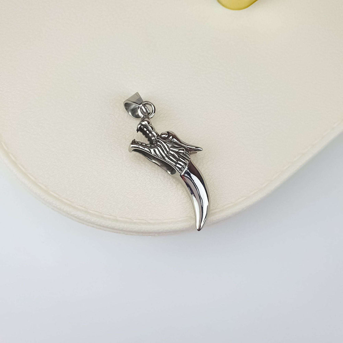 Steel wolf head and fang pendant on a light background