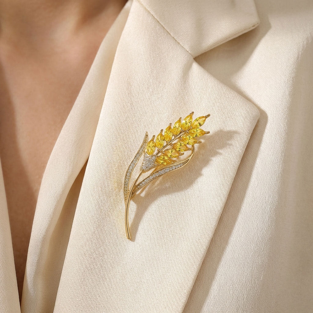 Wheat ear brooch with yellow crystals pinned to the lapel of a cream jacket