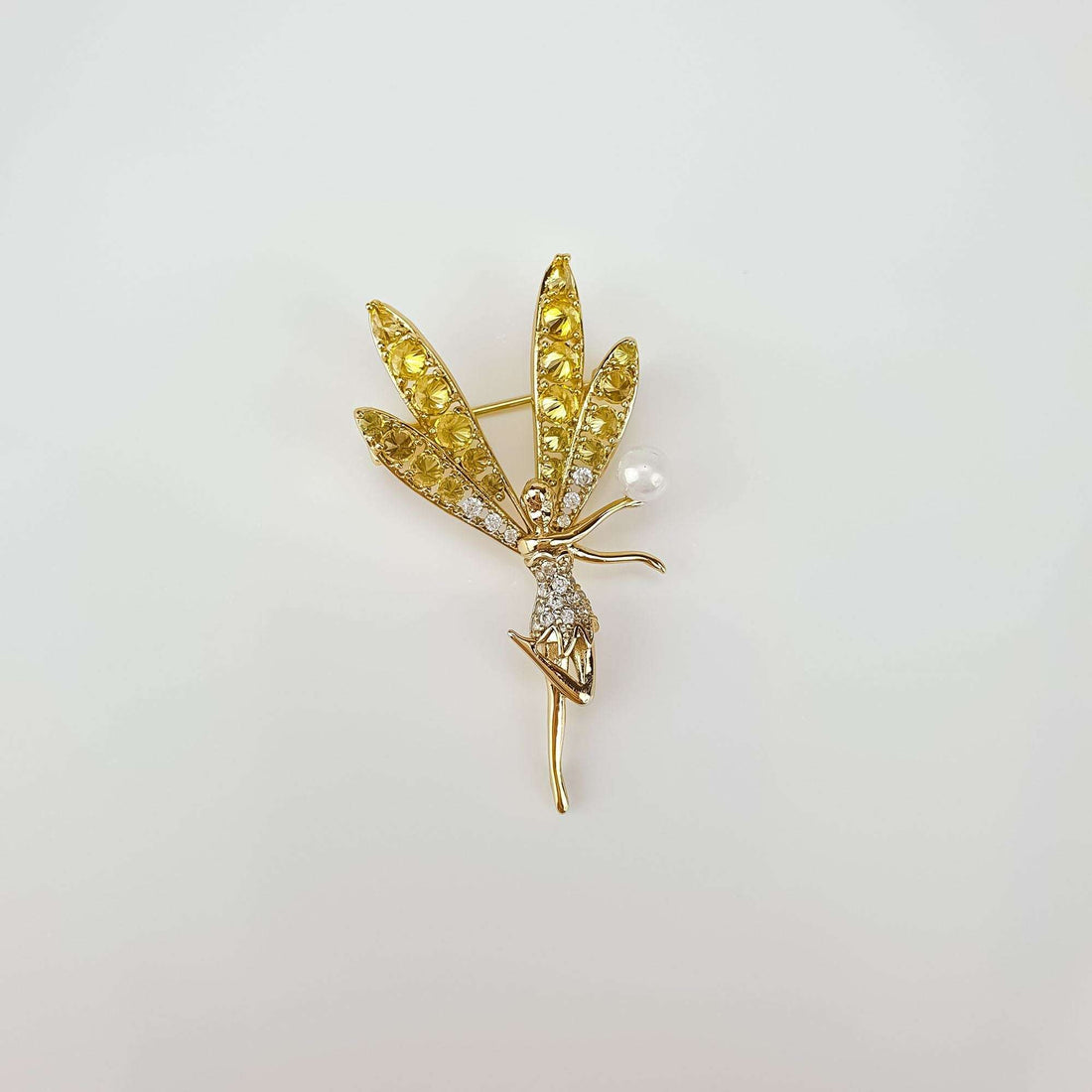 Gold-tone fairy brooch side view on grey, pin and clear stones visible