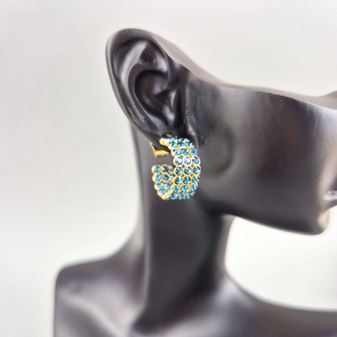 Blue crystal earring on a mannequin ear, gold-plated half-hoop with three rows