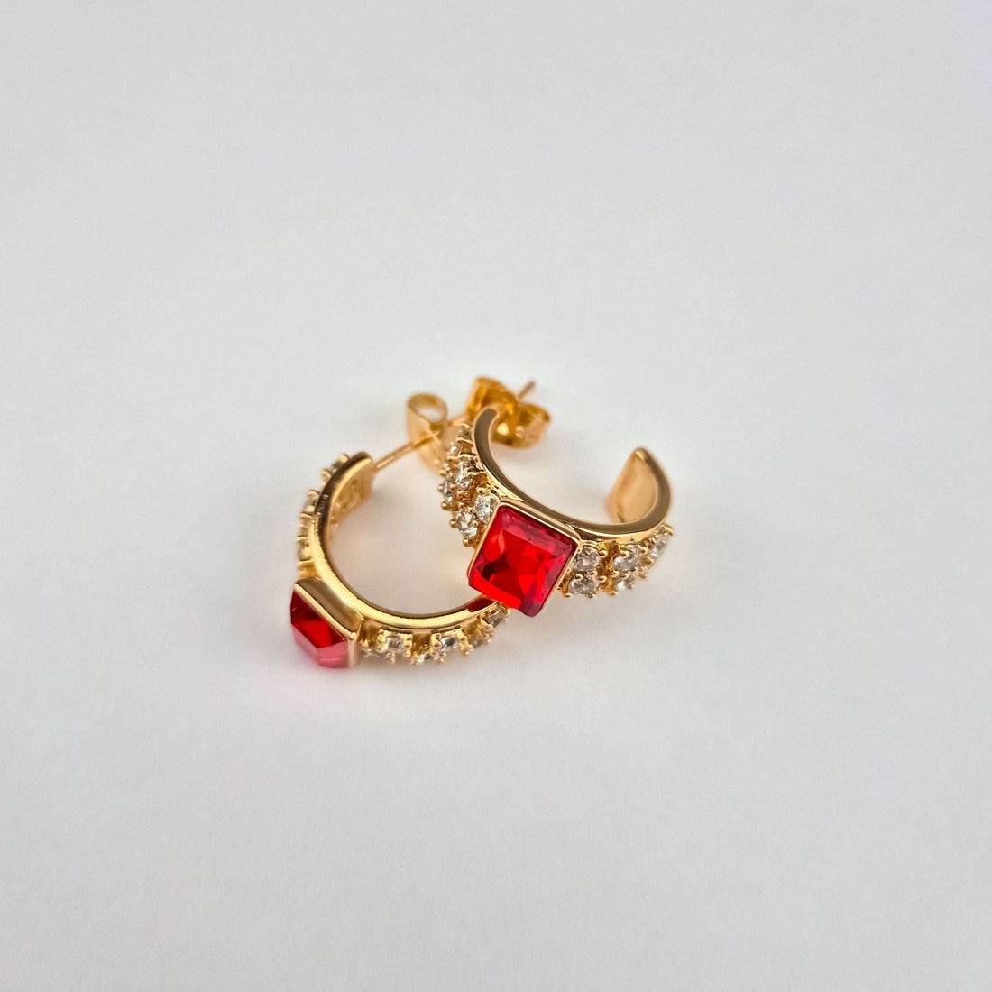 Red stone earrings at an angle showing the half-hoop shape and post