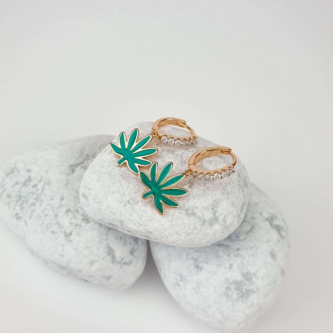 Green enamel leaf earrings with zirconia-set gold-plated clasps on white pebbles