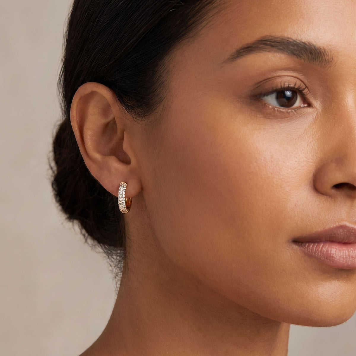 Gold-tone hoop earrings with cubic zirconia on white pebbles, clasp visible