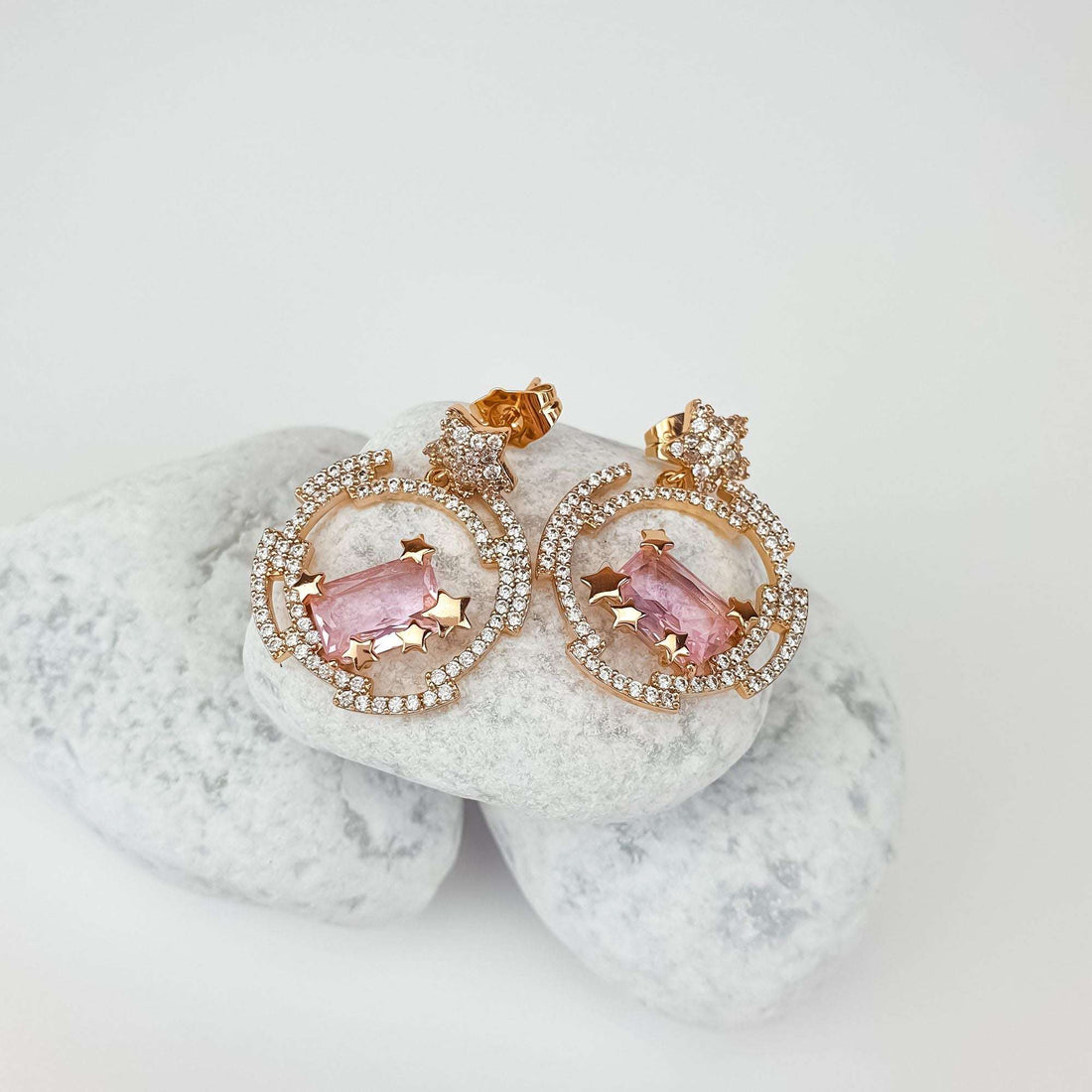 Star earrings with a pink crystal and push-back studs on white pebbles