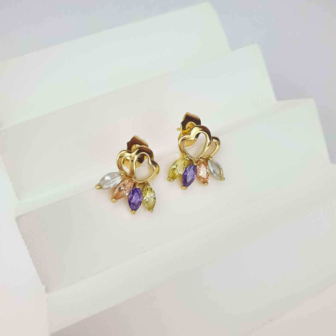 Heart stud earrings at an angle on a white stand, pastel marquise crystals