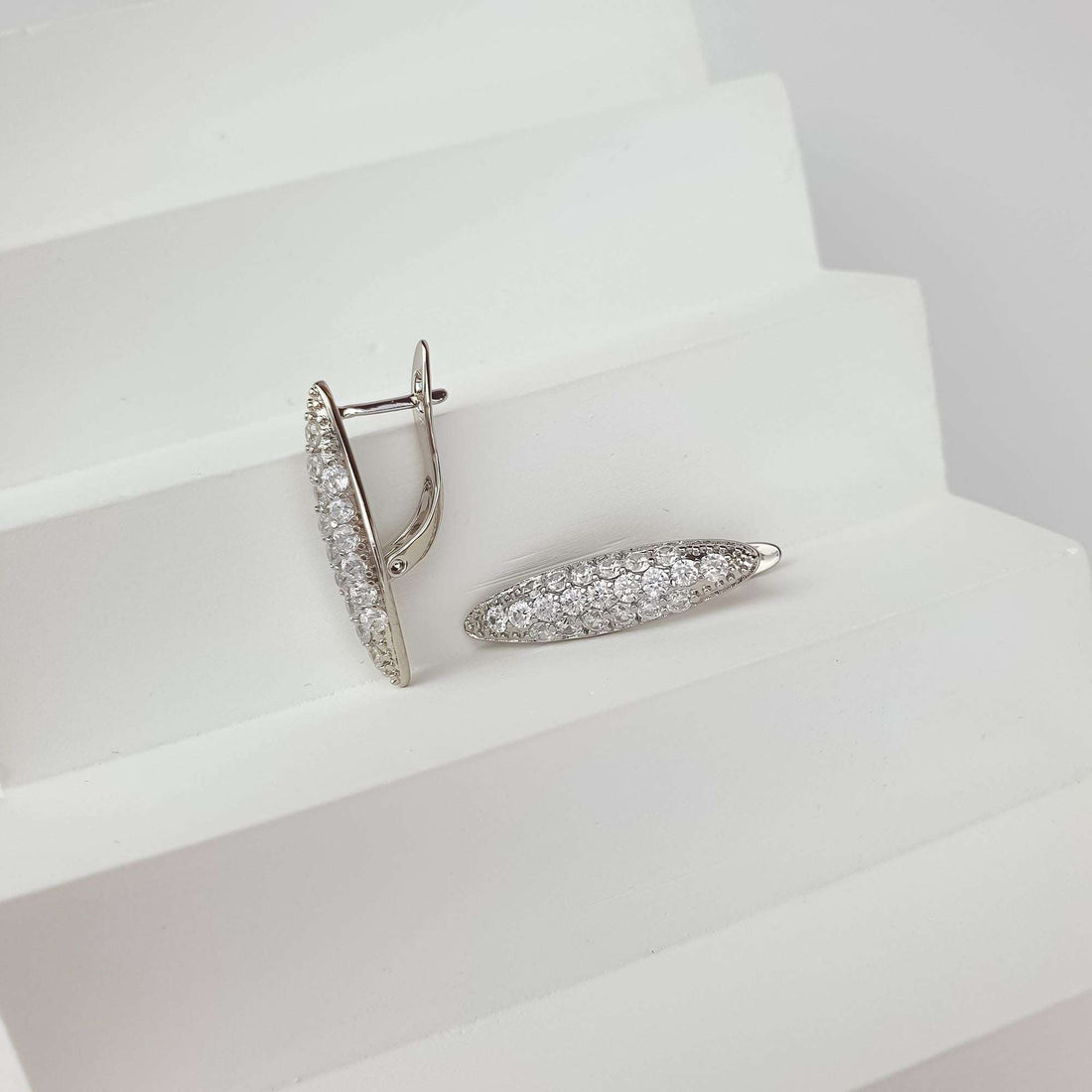 Silver-tone earrings from the side, showing the leverback clasp and dense crystal row