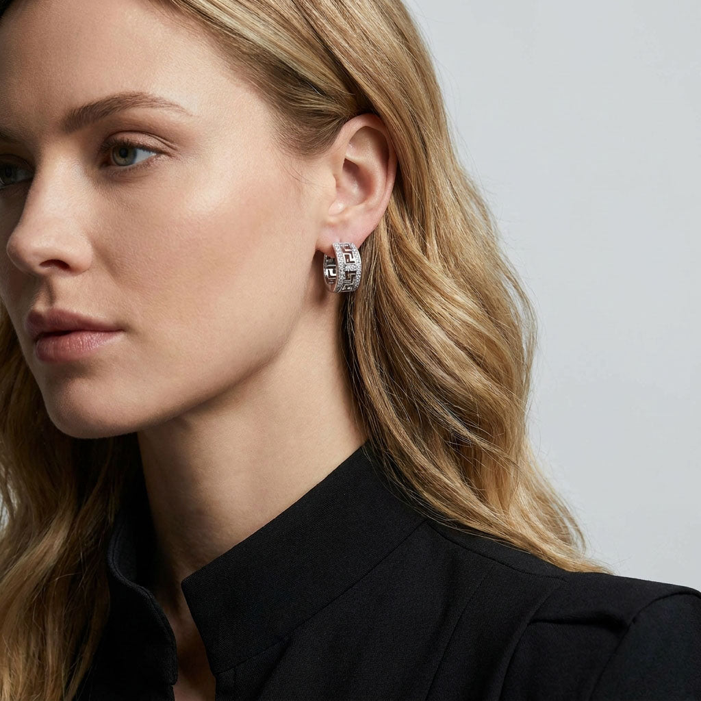 Silver-tone Greek key earring on a blonde model wearing a black jacket
