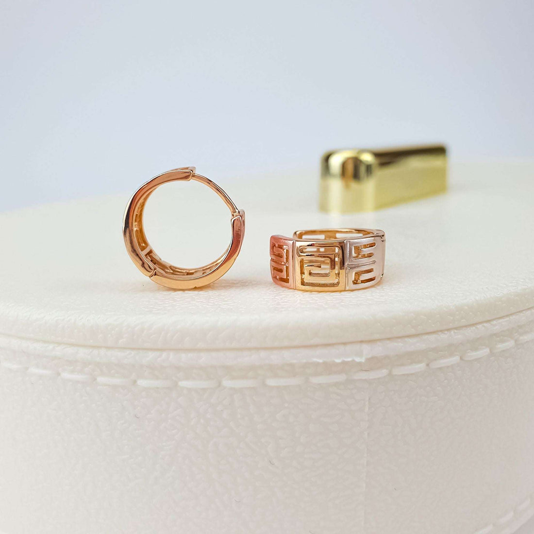 Meander earrings on a light leather pad, side view showing the leverback
