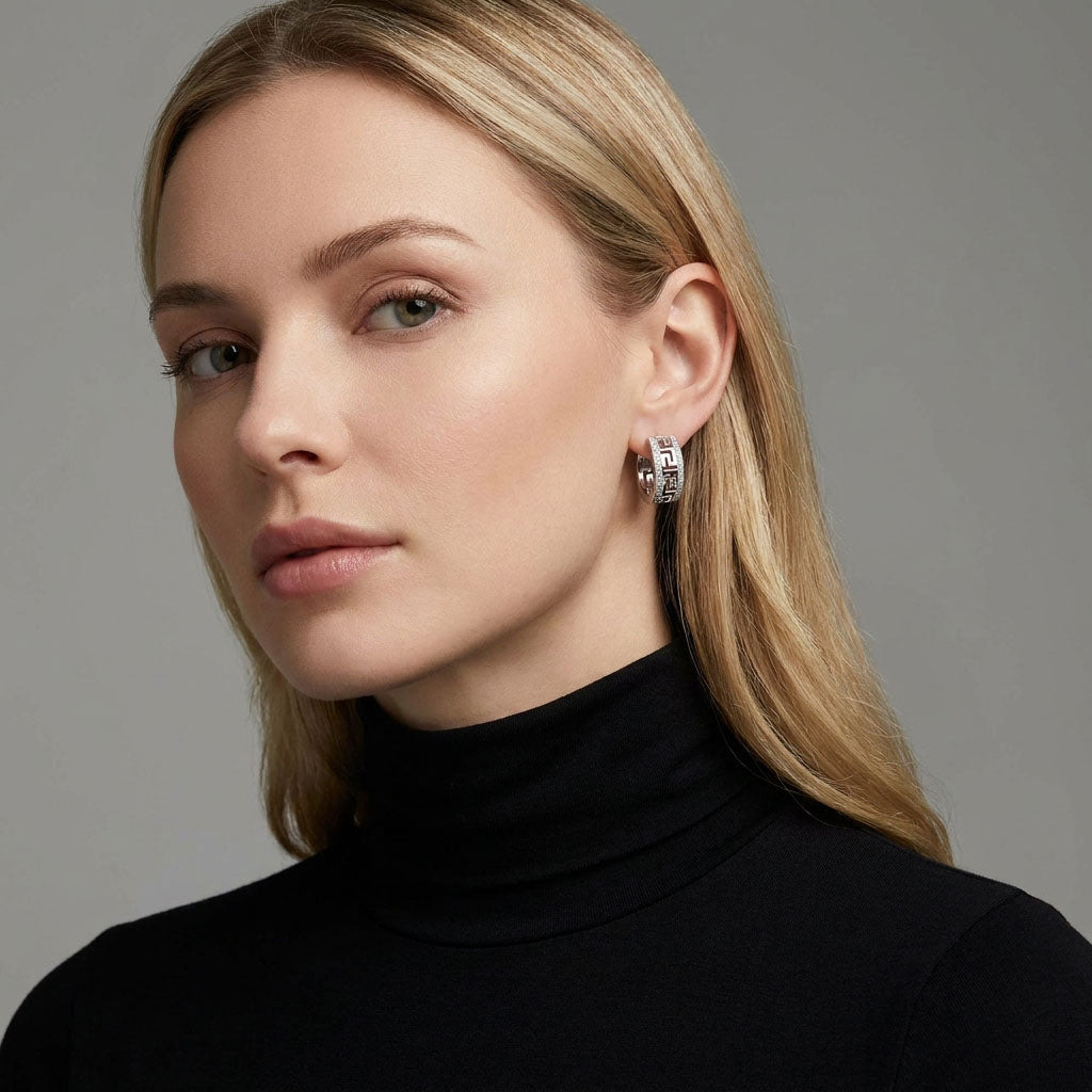 Model in a black polo-neck wearing a silver-tone Greek key earring with stones