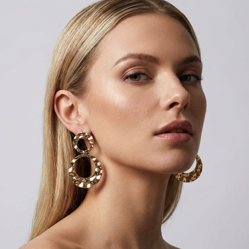 Model wearing large gold-plated double-circle earrings with a shimmering hammered surface