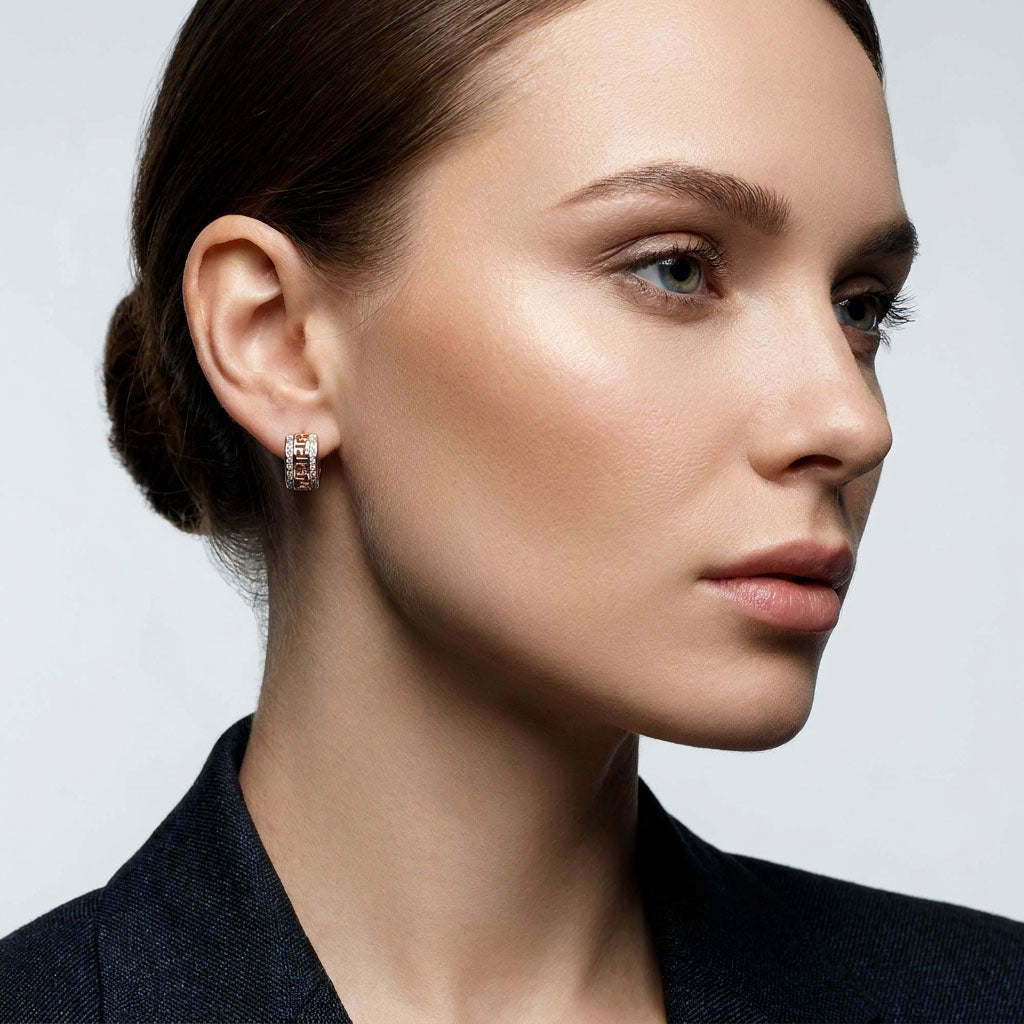 Woman in a dark jacket wearing gold-tone Greek pattern hoop earrings
