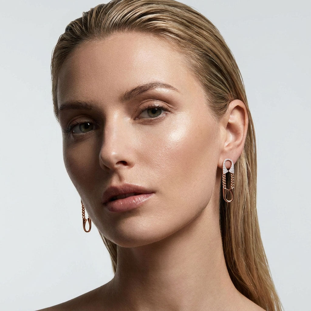 Model wearing long asymmetric gold-plated chain earrings with cubic zirconia