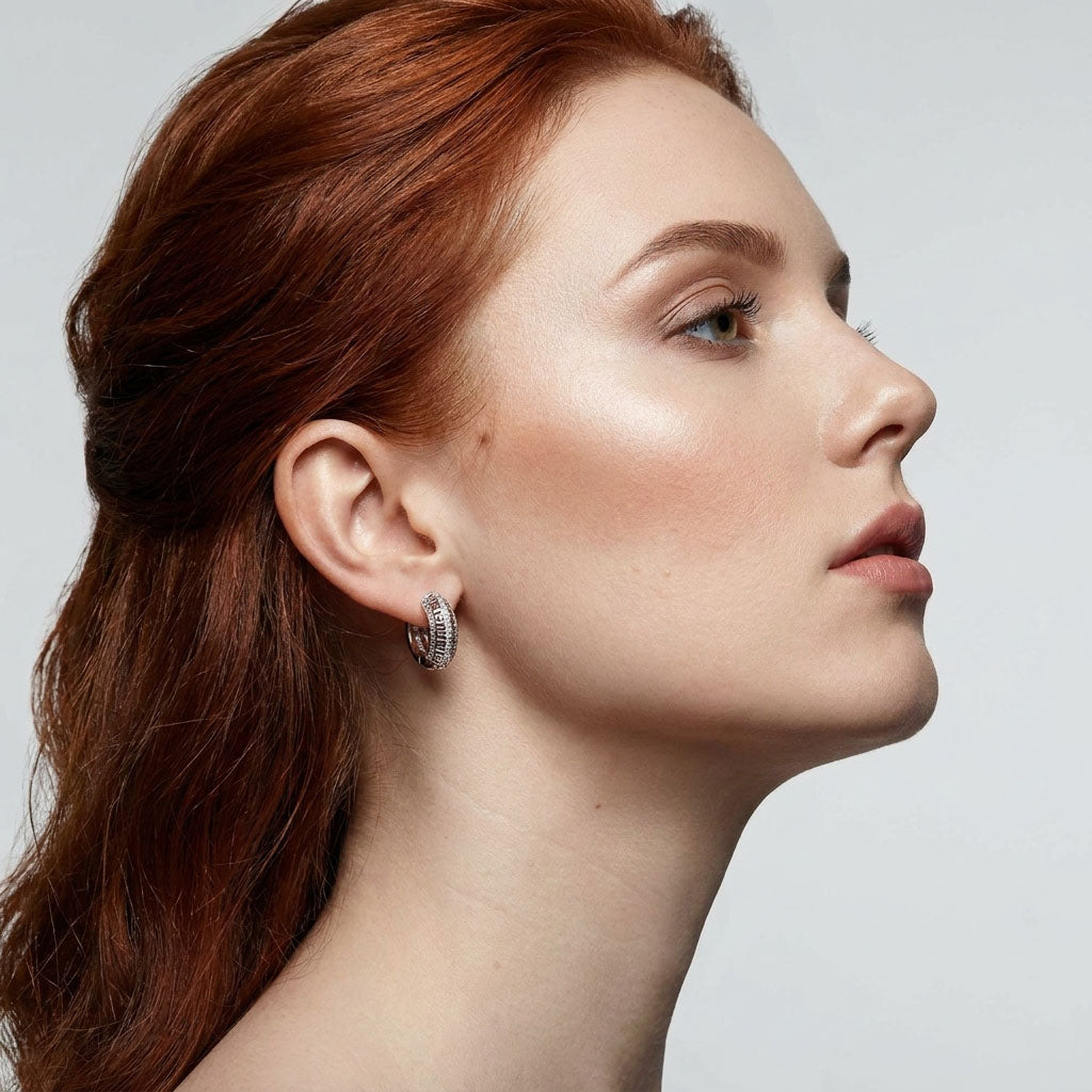 Model in profile wearing wide silver-tone Greek key hoop earrings