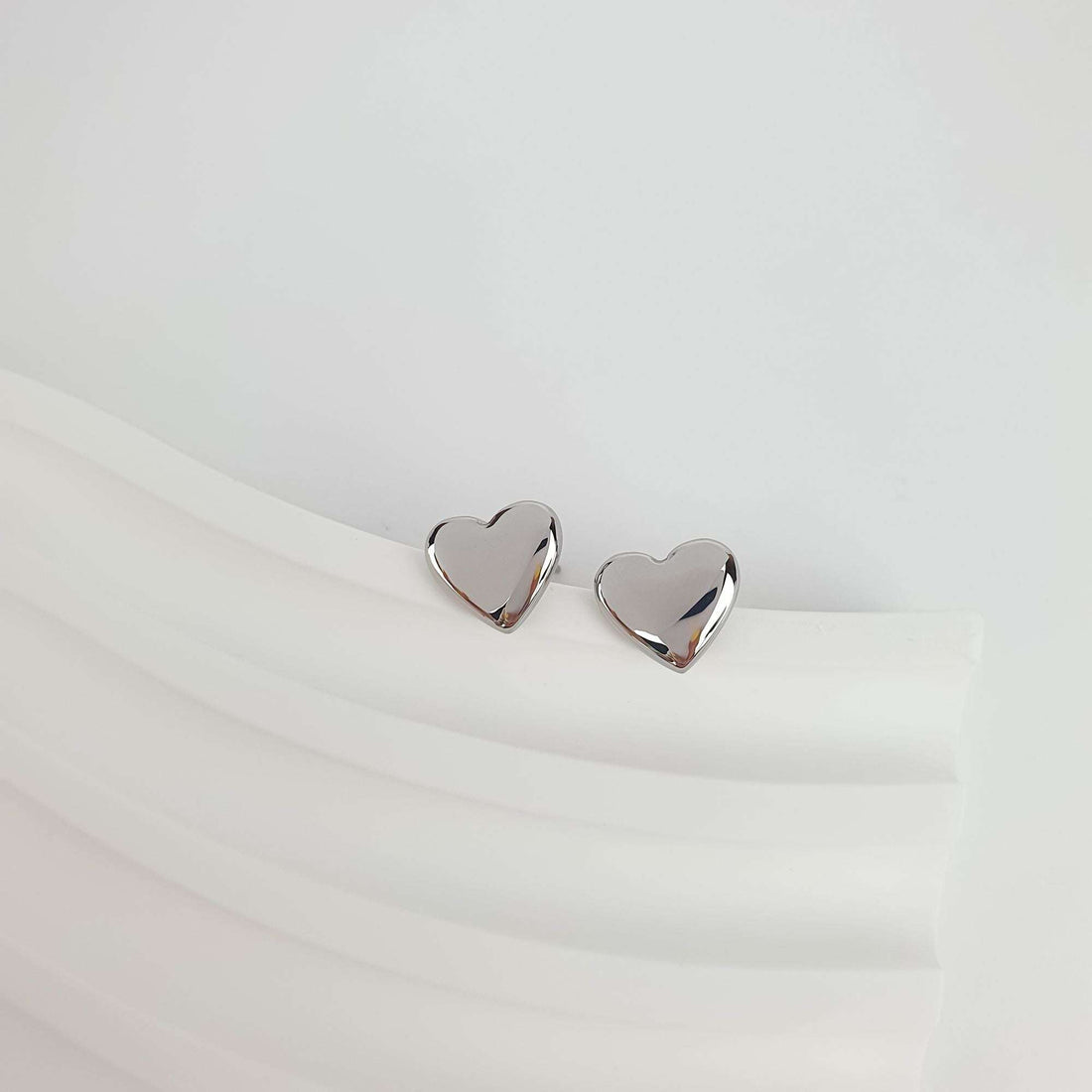 Silver-tone heart studs on a wavy white surface