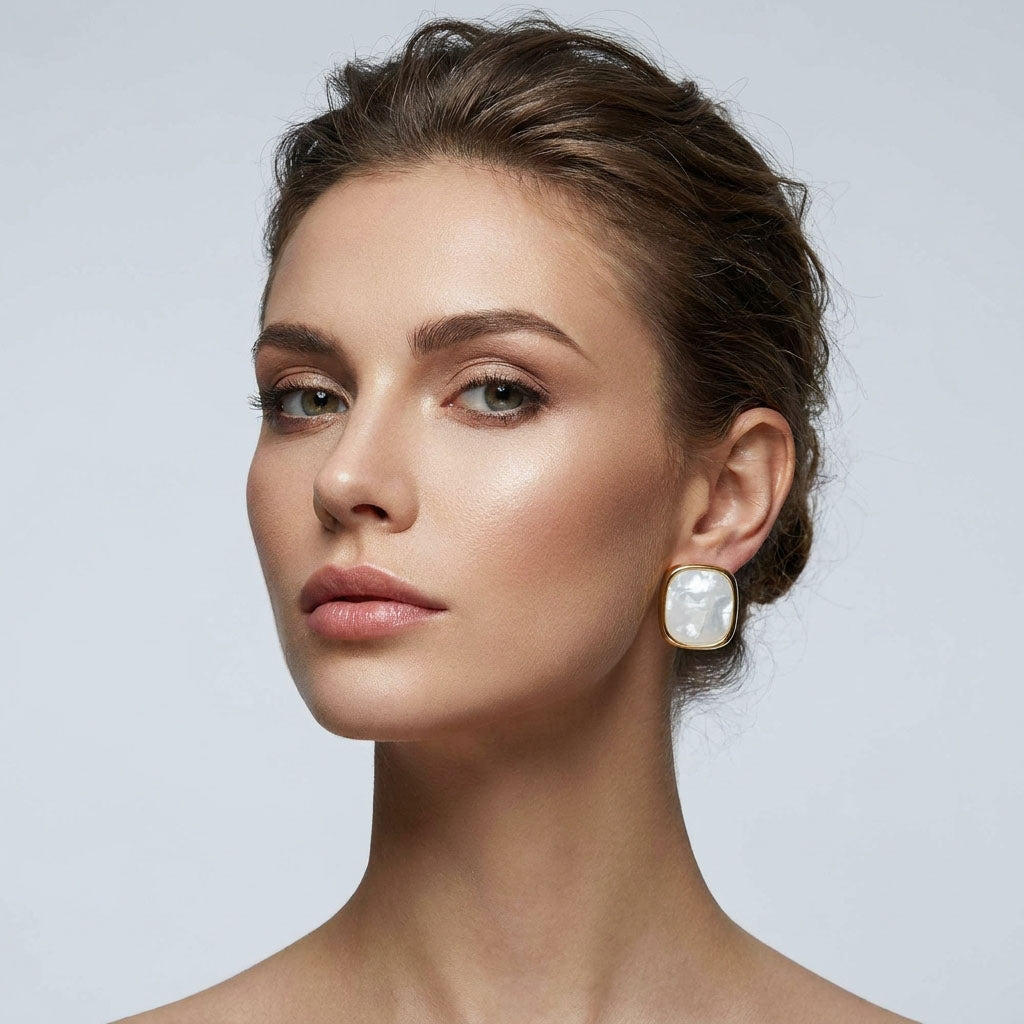 Close-up of a model wearing a gold-tone pearlescent square earring