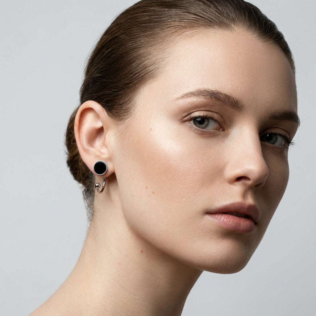 Model wearing a black enamel earring with a half-circle curving under the lobe